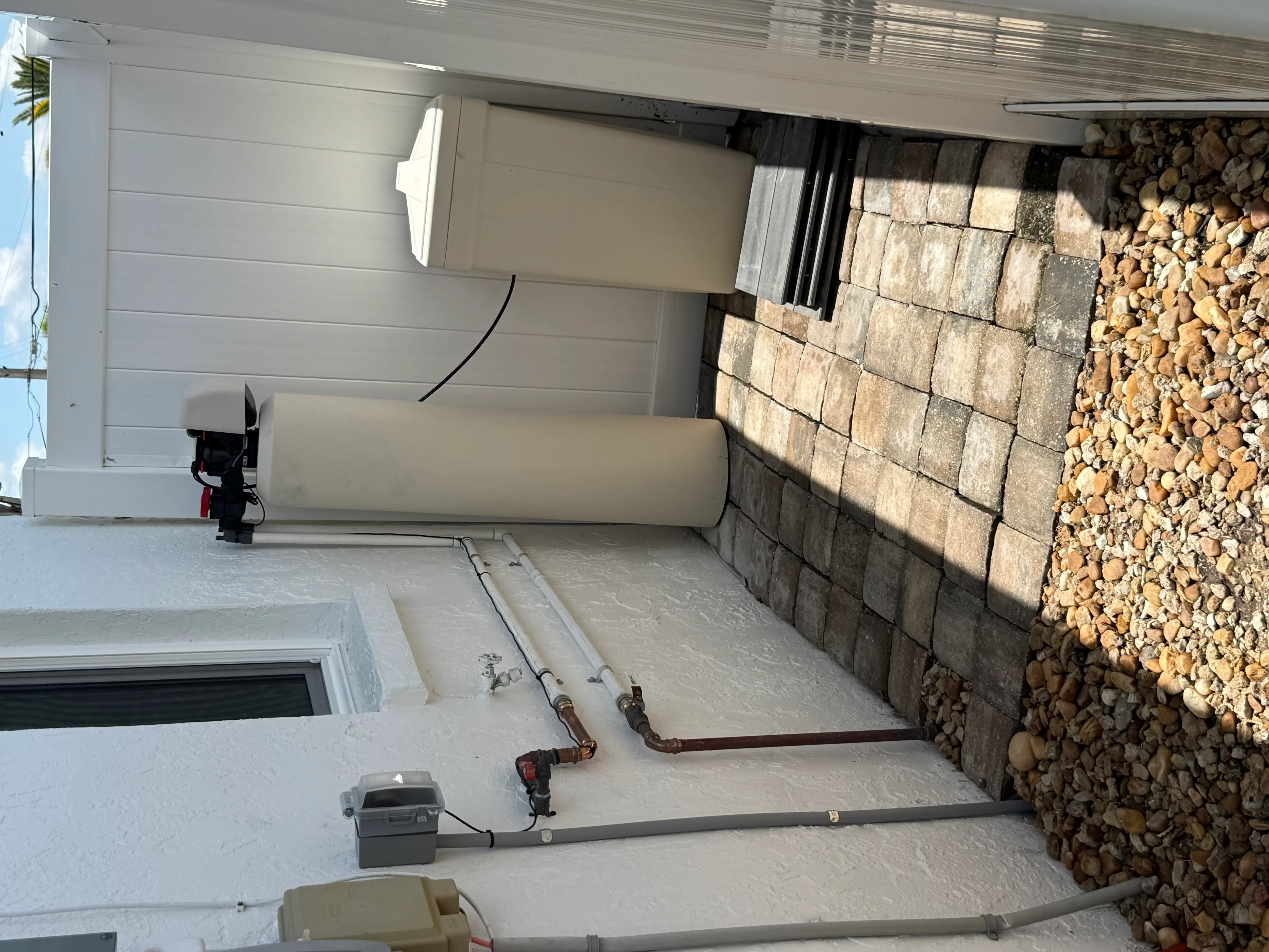 Garage plumbing installation with copper and PVC pipes on concrete floor