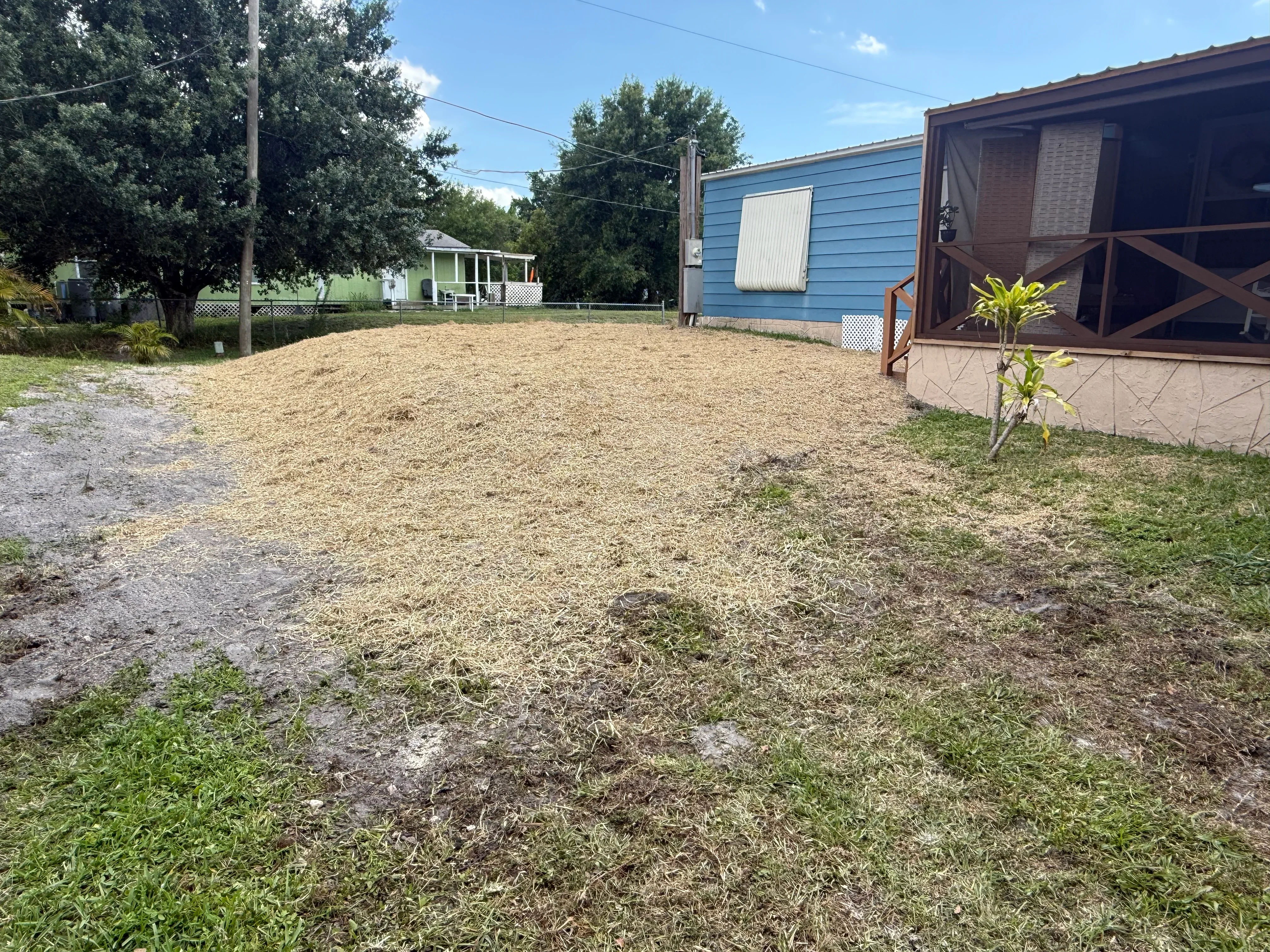 Excavated yard with gravel base preparation for septic system installation, mobile homes visible in background