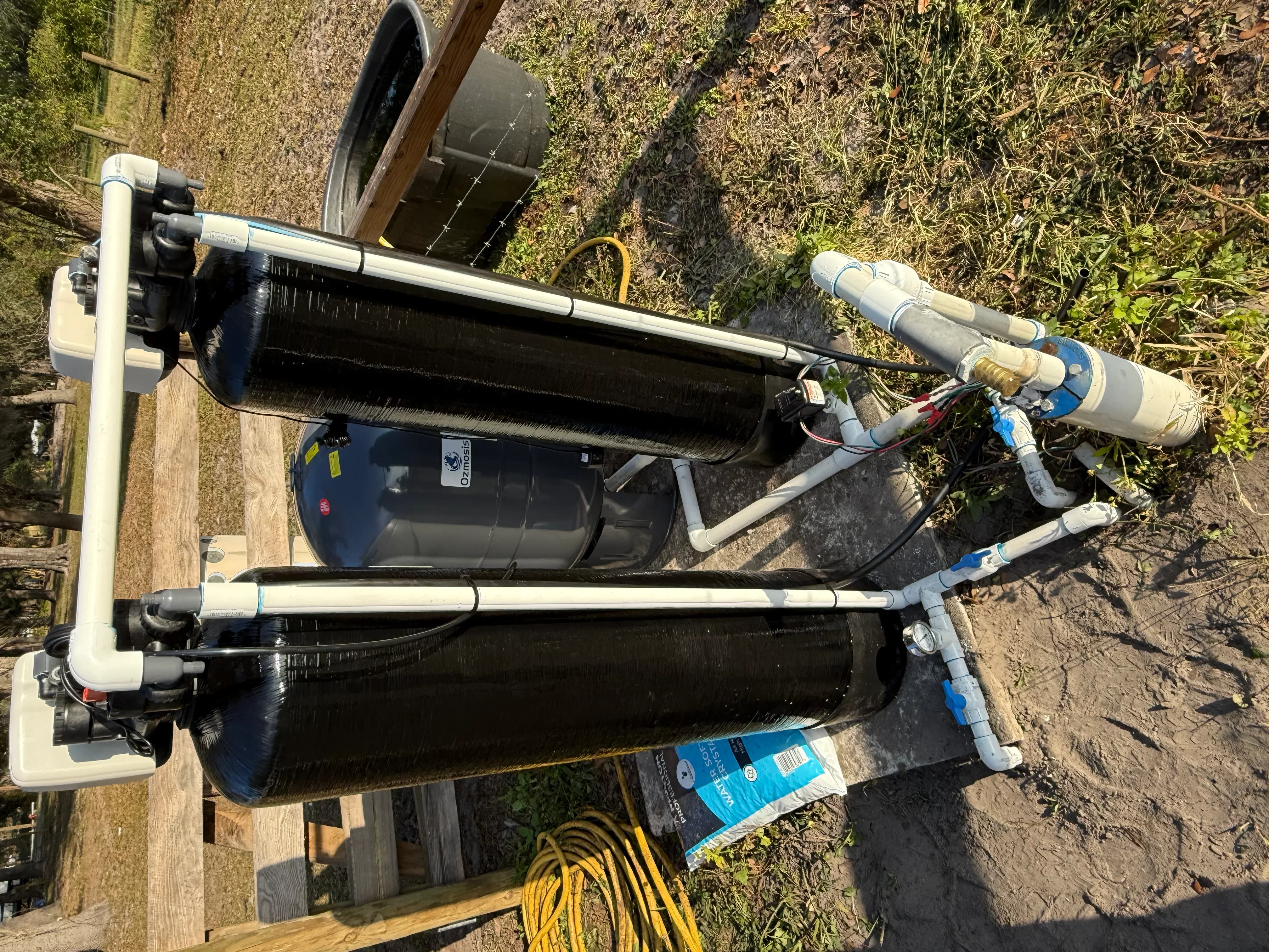 Dual tank water treatment system with carbon filters and blue ball valves installed outdoors