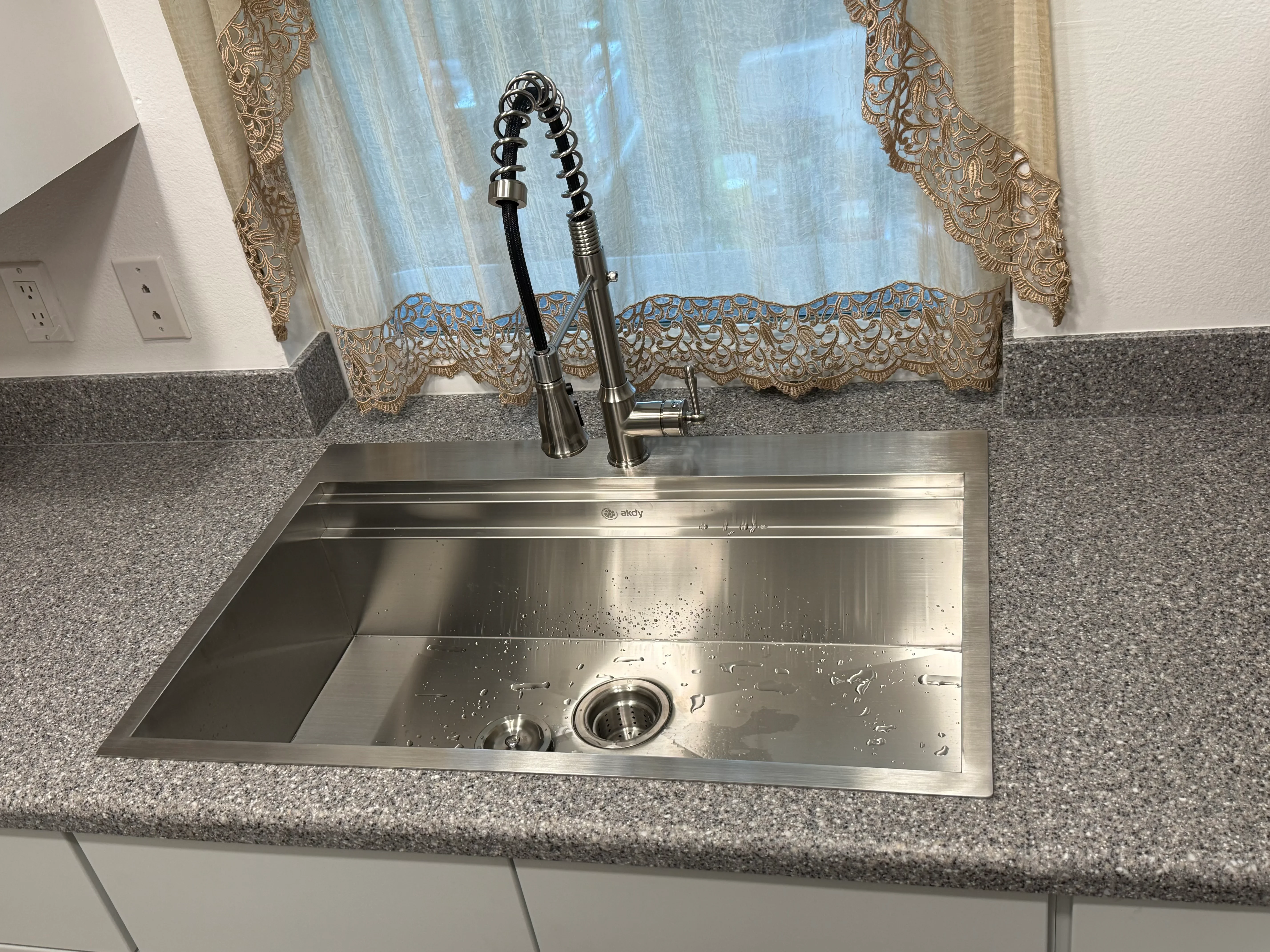 Stainless steel undermount kitchen sink with pull-down faucet installed in granite countertop