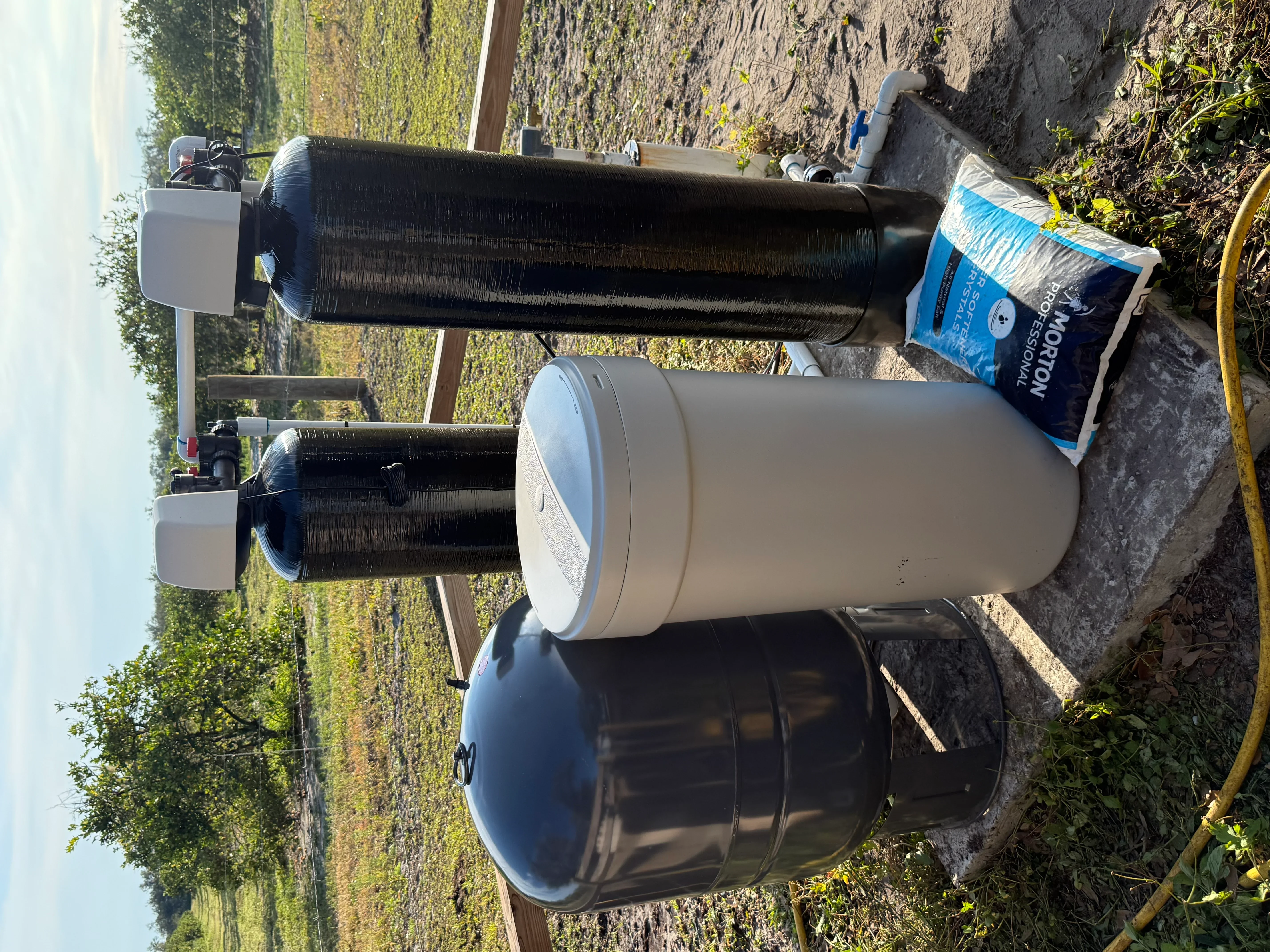 Water treatment system with carbon filter, softener tank, and storage tank installed outdoors