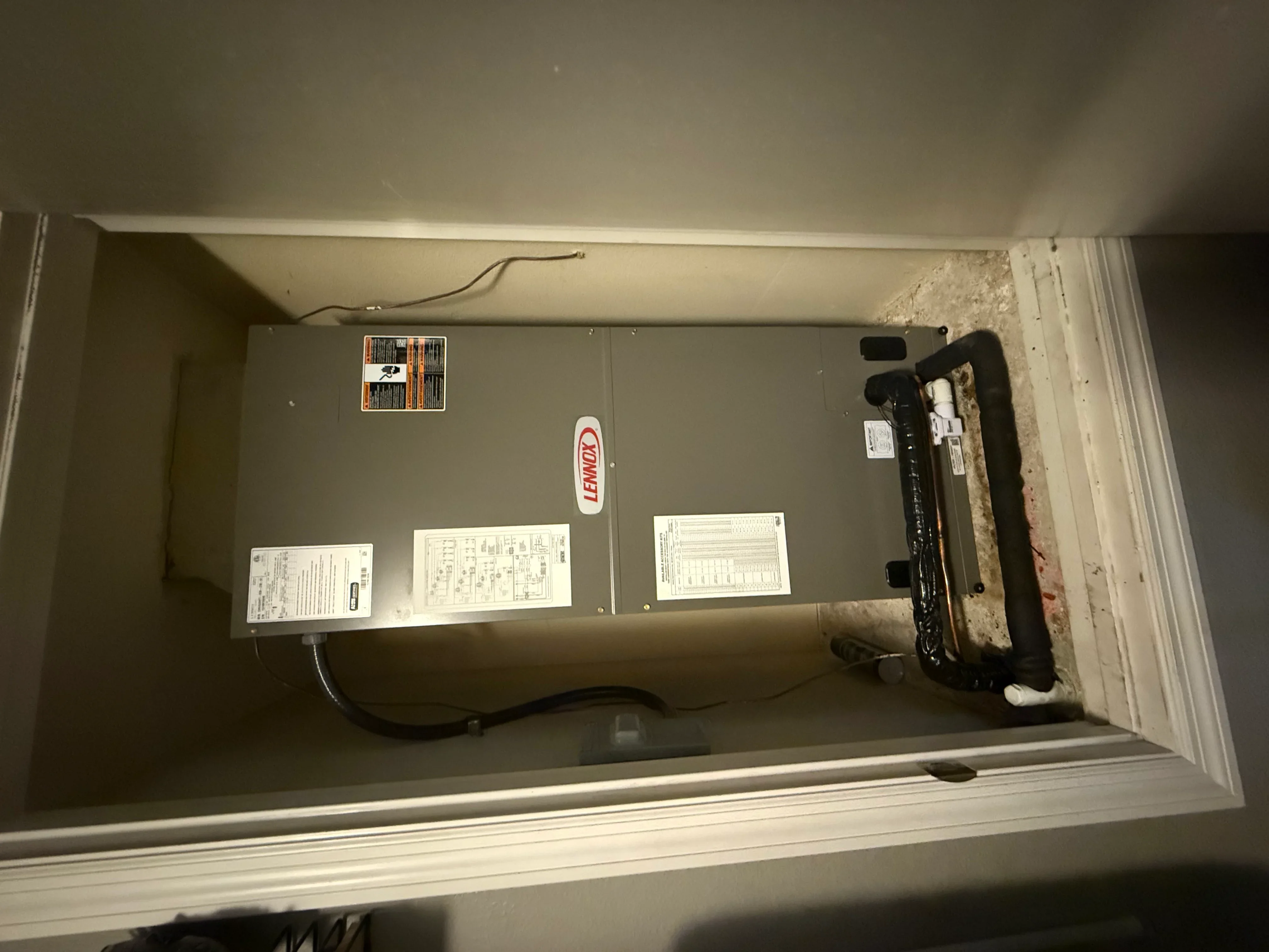 Installed Lennox water heater with electrical connections and documentation labels in utility closet
