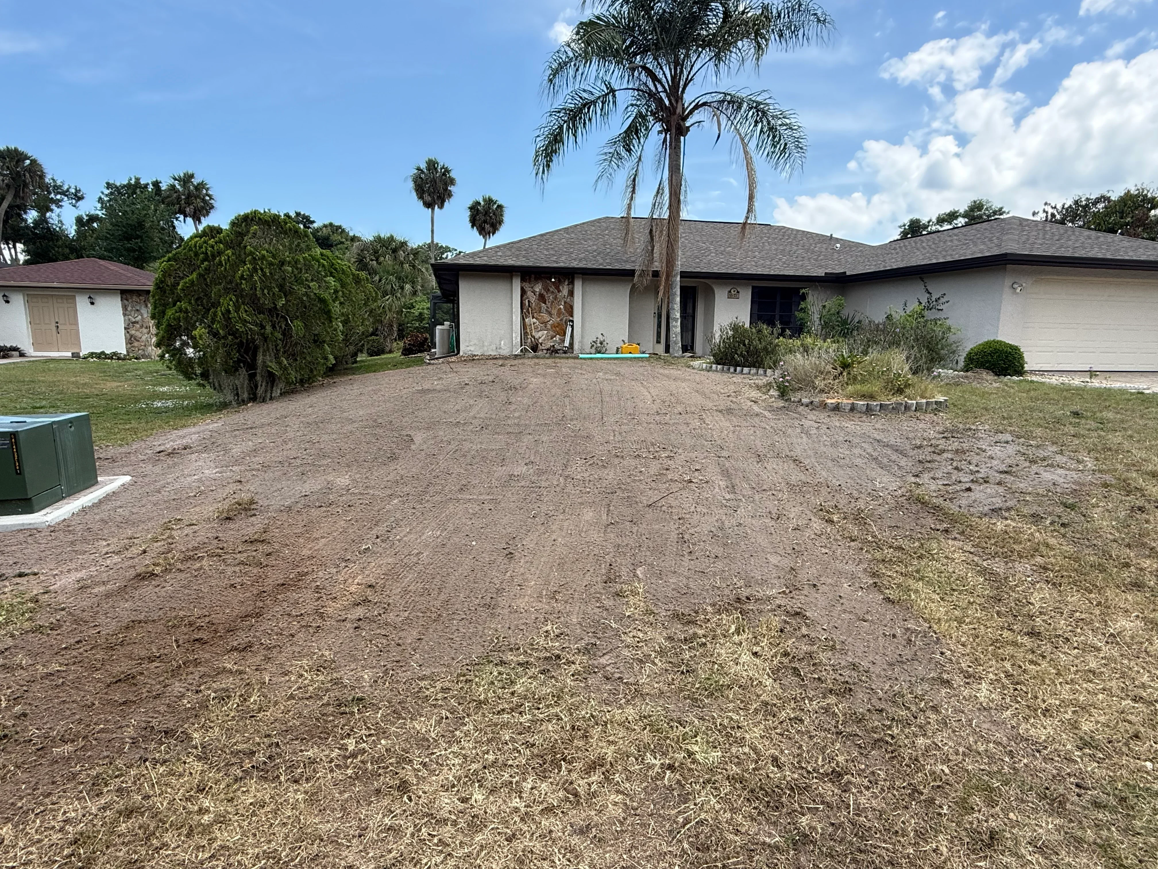 Freshly graded residential driveway with white stucco home and mature palm trees in Punta Gorda