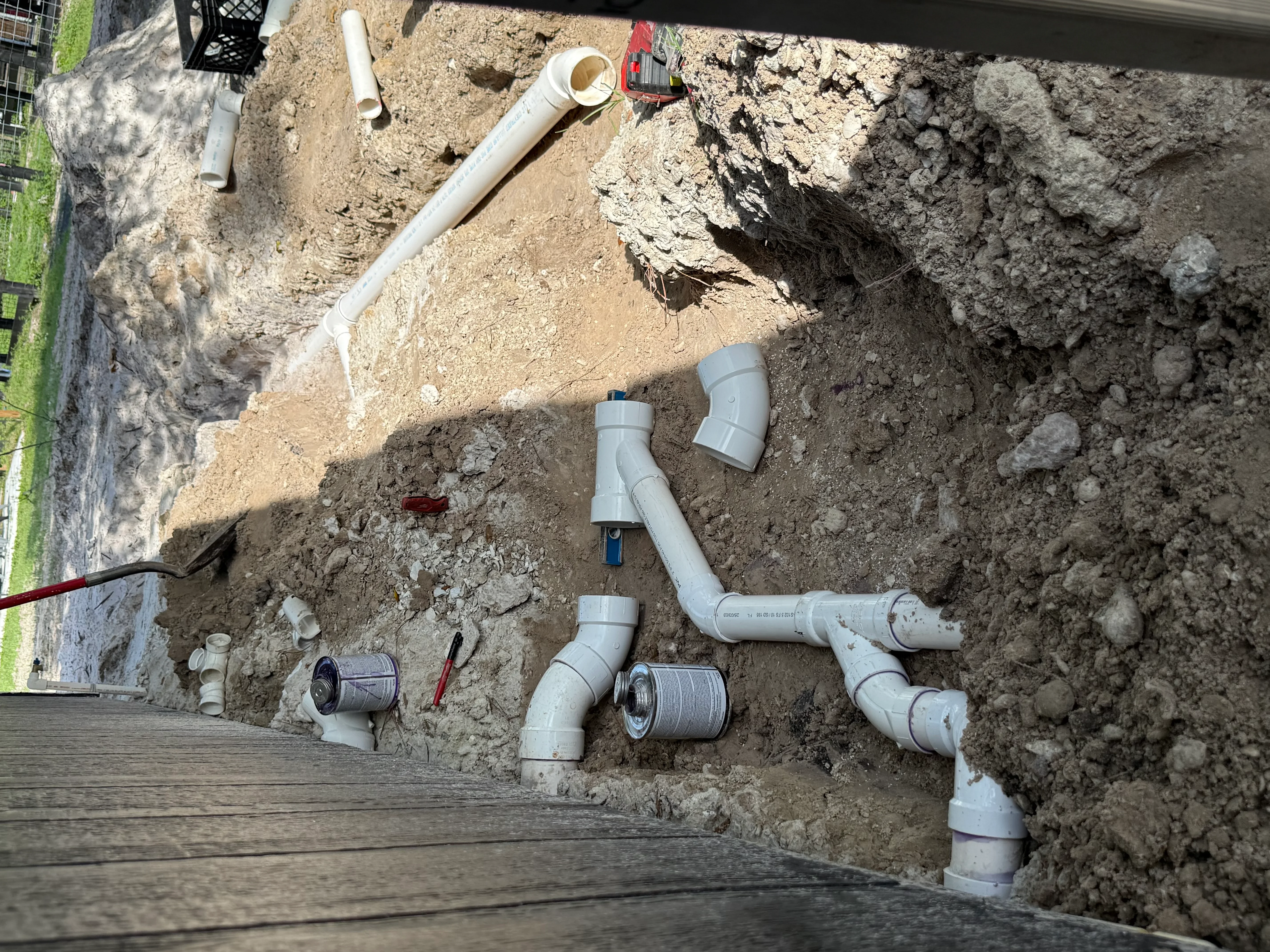 PVC drainage pipes and fittings installed in excavated soil foundation area