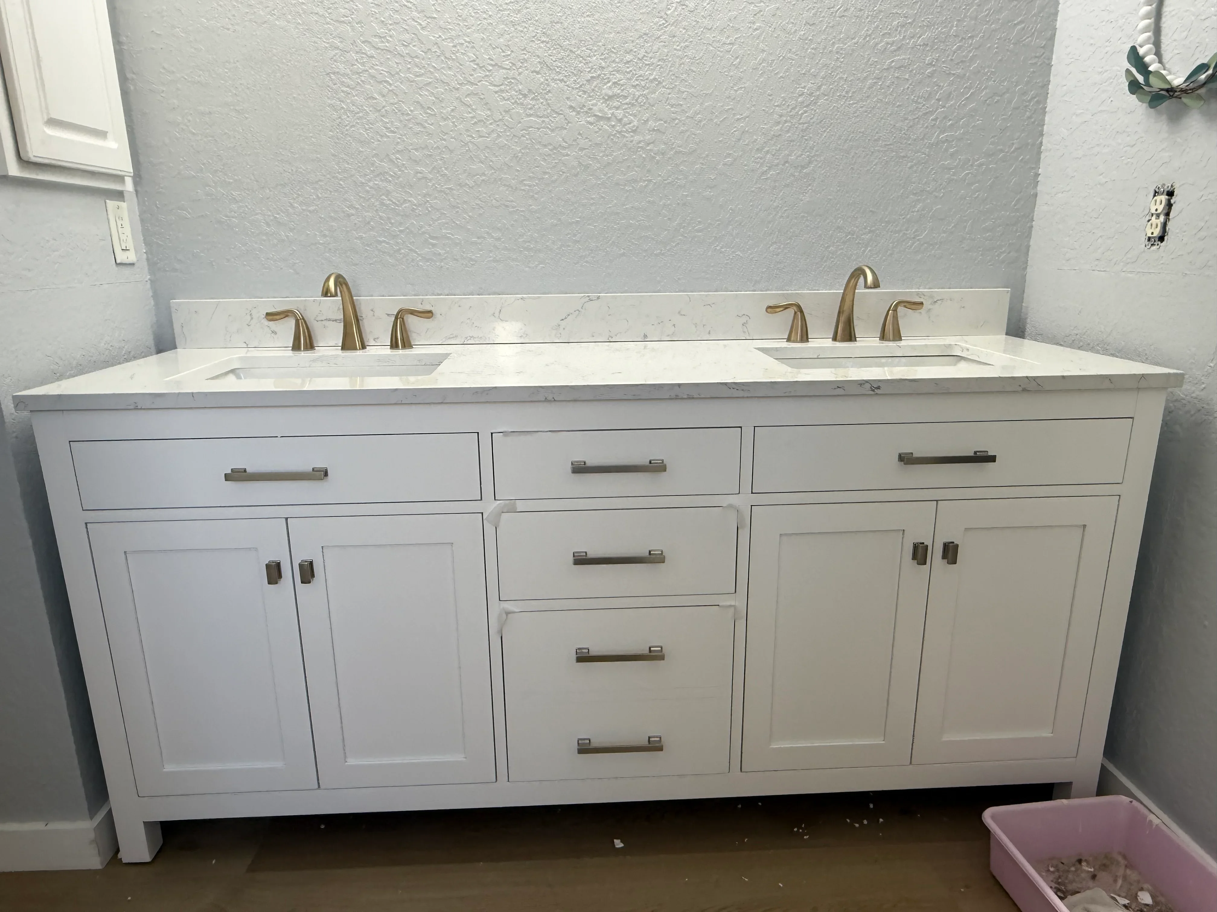 White dual-sink bathroom vanity with brass faucets and marble countertop