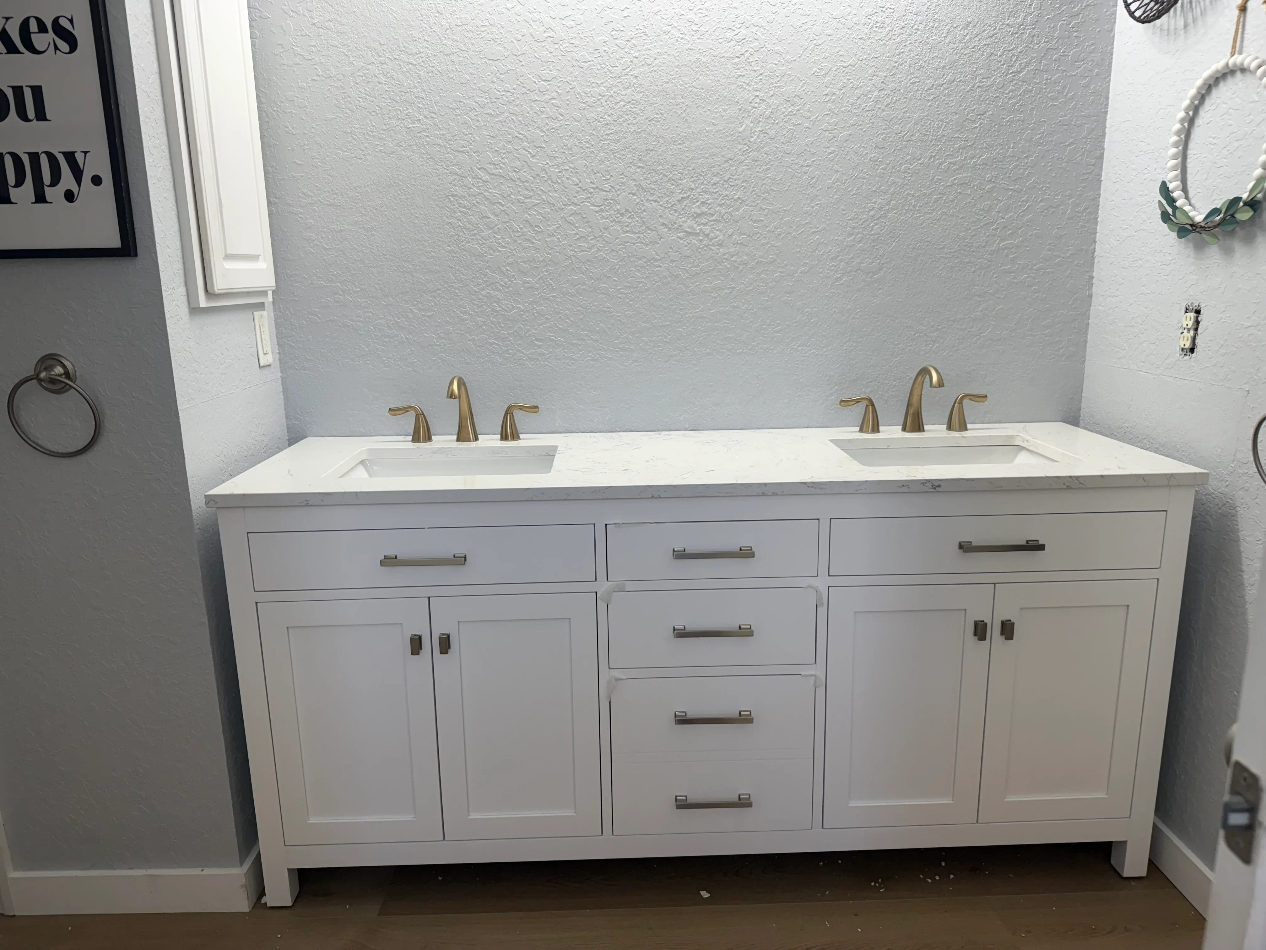 White dual sink bathroom vanity with brushed gold faucets and quartz countertop